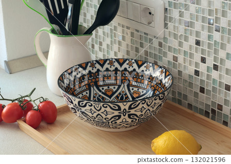 Retro-style ceramic bowl with geometric, floral patterns. Food in kitchen. Interior design and style. Mosaic tiles and kitchen countertops. Retro-style ceramic bowl with geometric, floral patterns. Food in kitchen. Interior design and style. Mosaic tiles and kitchen countertops. 132021596