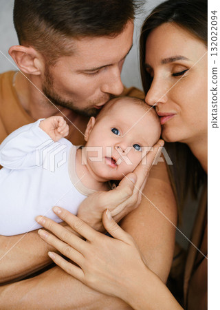 Parents Holding Baby And Kissing Gently 132022094
