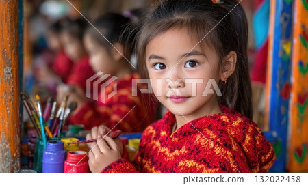 A young girl, with an artistic eye, poses while painting, the focus is on her, with bright colors and art supplies surrounding her 132022458