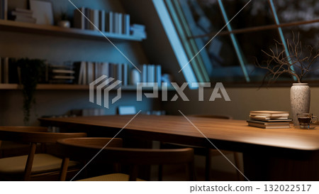 A coffee cup on wooden table and armchairs next to a bookshelf in the dim room with roof window. 132022517