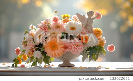A serene angel figurine adorns a beautiful arrangement of peach and white flowers in a classic urn, creating a peaceful, memorial-like scene 132022631