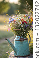 Rustic Flower Vase in Sunlit Garden.Turquoise watering can with wildflowers on grass, glowing in warm sunlight. Perfect for spring, nature, and romantic themes. 132022742