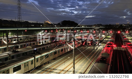 A night view of Tokyu Corporation's Nagatsuta Inspection Yard, where many Tokyu trains are parked. In the background is the light trail of a JR Yokohama Line train. 132022798