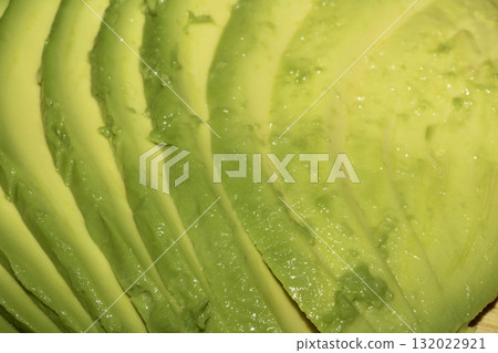 Close up of green fresh avocado sliced on chopping board Close up of green fresh avocado sliced on chopping board 132022921