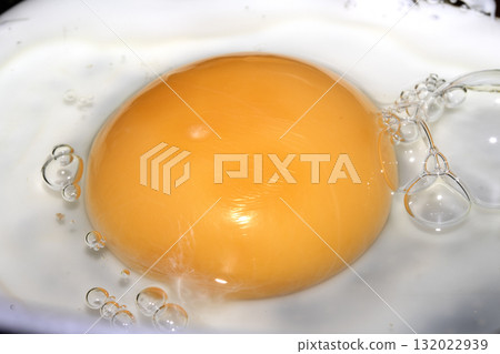 Close up of Fresh egg frying in a pan with golden yolk Close up of Fresh egg frying in a pan with golden yolk 132022939