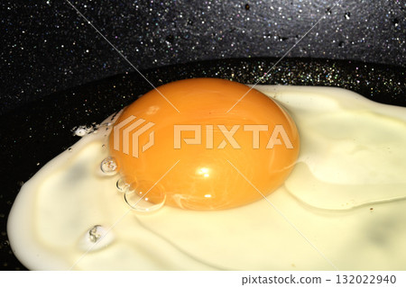 Close up of Fresh egg frying in a pan with golden yolk Close up of Fresh egg frying in a pan with golden yolk 132022940
