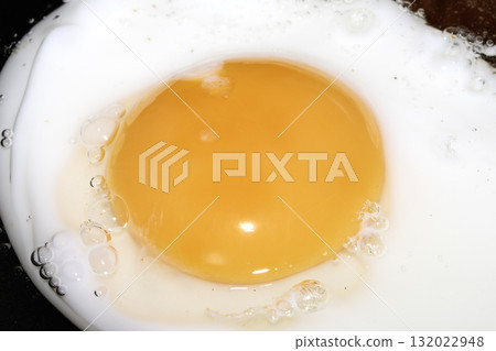 Close up of Fresh egg frying in a pan with golden yolk 132022948