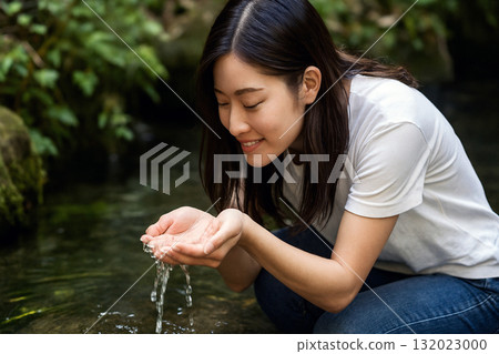 A woman scooping spring water with her hands 132023000