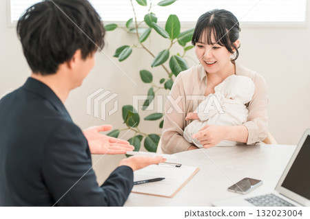 A mother holding a baby receiving advice from a salesman during a door-to-door sales call, a female customer 132023004