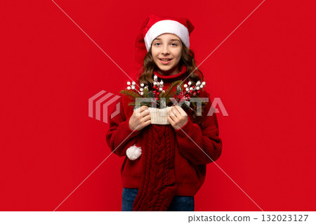 Smiling girl in Santa hat holds Christmas stocking filled Smiling girl in Santa hat holds Christmas stocking filled 132023127