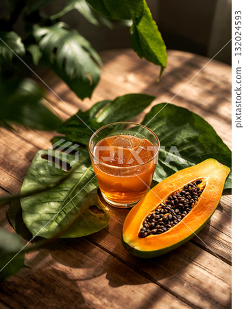 Healthy tropical summer refreshment. A glass of cold-pressed papaya juice with a ripe fruit half on a wooden background, creating a serene and exotic vibe. Healthy tropical summer refreshment. A glass of cold-pressed papaya juice with a ripe fruit half on a wooden background, creating a serene and exotic vibe. 132024593