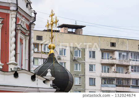 The dome of an Orthodox church against the backdrop of a panel apartment building in Russia. Contrasts of Modern Russia. Faith and Everyday Life The dome of an Orthodox church against the backdrop of a panel apartment building in Russia. Contrasts of Modern Russia. Faith and Everyday Life 132024674