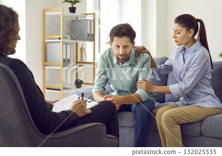 Young couple sitting on sofa and talking with psychologist on therapy session. 132025535