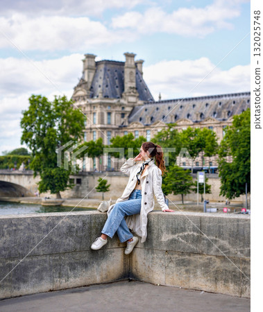 Woman sitting near Louvre Museum and Pont Royal bridge in Paris Woman sitting near Louvre Museum and Pont Royal bridge in Paris 132025748