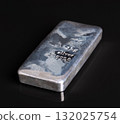 Cast silver bar, side view on black glass plate and background. Silver ingot with an irregular surface created by the cooling of the liquid metal. Stamped with 1 kg for the weight, and 999,0 purity. 132025754