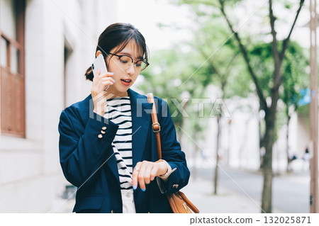 一名年輕女子一邊打電話一邊走在街上 132025871