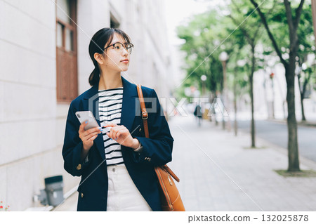 一位年輕女子一邊看著智慧型手機一邊尋找商店 132025878