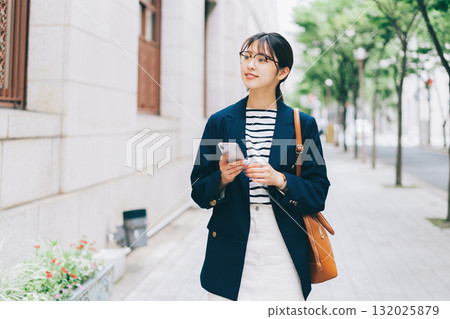 A young woman searching for a store while looking at her smartphone 132025879