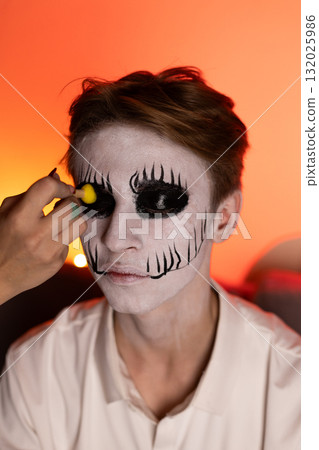 A model is getting their face painted for a Halloween costume 132025986