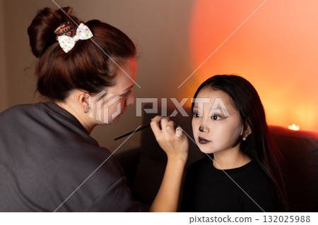 Woman paints little girl's face with a butterfly design at a children's festival 132025988