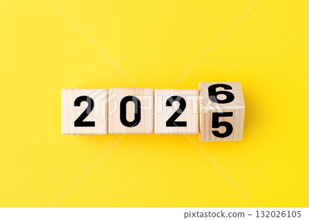Wooden cubes with alternating numbers of 2026 on the yellow background. New Year's card 132026105