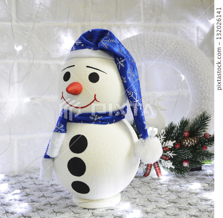 snowman in a blue cap and with a kind smile against the background of a garland snowman in a blue cap and with a kind smile against the background of a garland 132026141