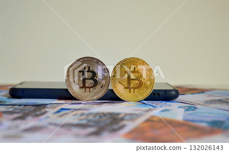 Two Bitcoin coins against a backdrop of Russian rubles Two Bitcoin coins against a backdrop of Russian rubles 132026143