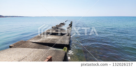 An old, dilapidated concrete pier extends into the sea An old, dilapidated concrete pier extends into the sea 132026157