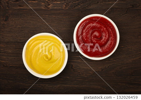 Bowls of tomato ketchup and mustard on table 132026459