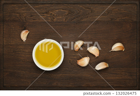 Olive oil and garlic cloves on rustic wooden cutting board 132026475