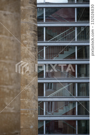 A view of a modern building that features a mix of stone and glass architecture A view of a modern building that features a mix of stone and glass architecture 132026830