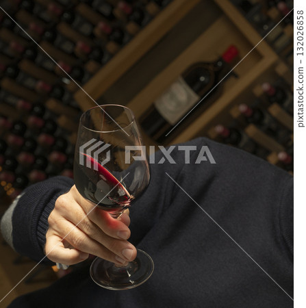 Enjoying red wine in a cozy wine cellar filled with bottles Enjoying red wine in a cozy wine cellar filled with bottles 132026858