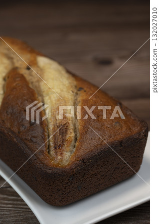 Freshly baked banana bread with golden crust served on a plate 132027010
