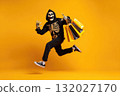 Happy man in skeleton grim reaper costume running and holding shopping bags, celebrating Halloween 132027170