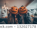Couple hiding faces with halloween pumpkins at home 132027178