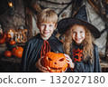 Children wearing halloween costumes holding a jack-o'-lantern 132027180