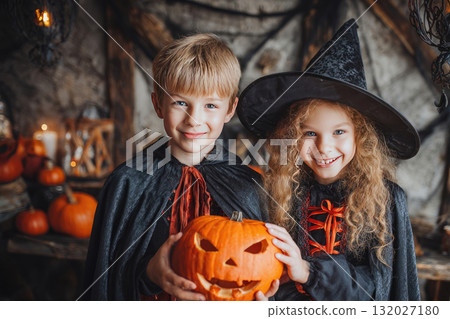 Children wearing halloween costumes holding a jack-o'-lantern 132027180