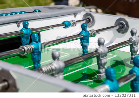 Close view of foosball table with blue and silver players shining under summer sunlight 132027311