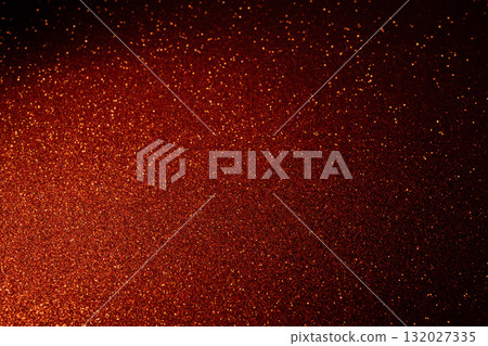 Red glitter background glowing from lower left with golden sparkles fading into shadows 132027335