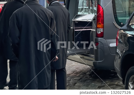Men workers of funeral service loading the coffin into the hearse 132027526