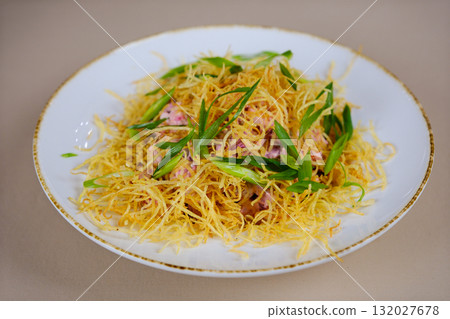 salad with dry fried potatoes Bowl of crispy vegetable salad topped with golden chips and fresh greens, served on a marble table, accompanied by bread and other dishes in the background. 132027678