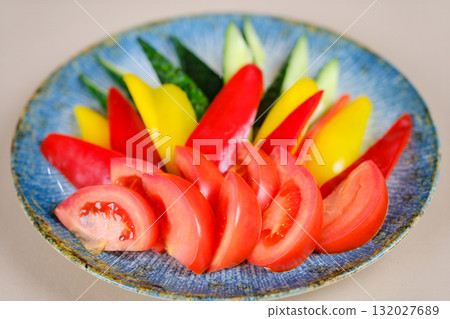 pepper, tomato, cucumber in pieces on a plate vegetables, jug of oil, bowl with vegetable, knife and fork on table 132027689