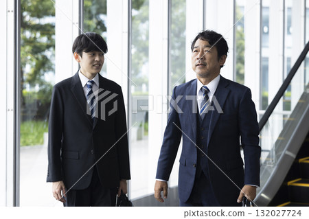 Businessman riding escalator 132027724