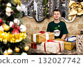 Happy joyful boy opening gift boxes during christmas celebration near new year tree 132027742