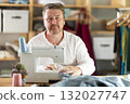 Happy middle-aged male dressmaker working with sewing-machine 132027747