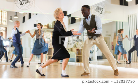 Man and elderly woman performing jazz dance in dancing room 132027750