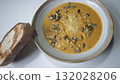 Bowl of creamy pumpkin soup topped with roasted seeds and parmesan cheese served with toasted bread. Concept of homemade comfort food, autumn flavors, and cozy seasonal din 132028206