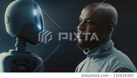 Man Smiling Warmly While Looking Futuristic AI Robot With Glowing Accents Man Smiling Warmly While Looking Futuristic AI Robot With Glowing Accents 132028385