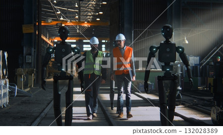 Engineers in Safety Vests Collaborate With Humanoid Robots Inside High Tech Industrial Facility 132028389