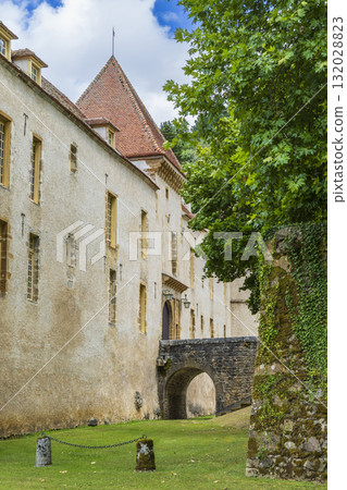 Chateau building featuring a stone bridge and green trees 132028823